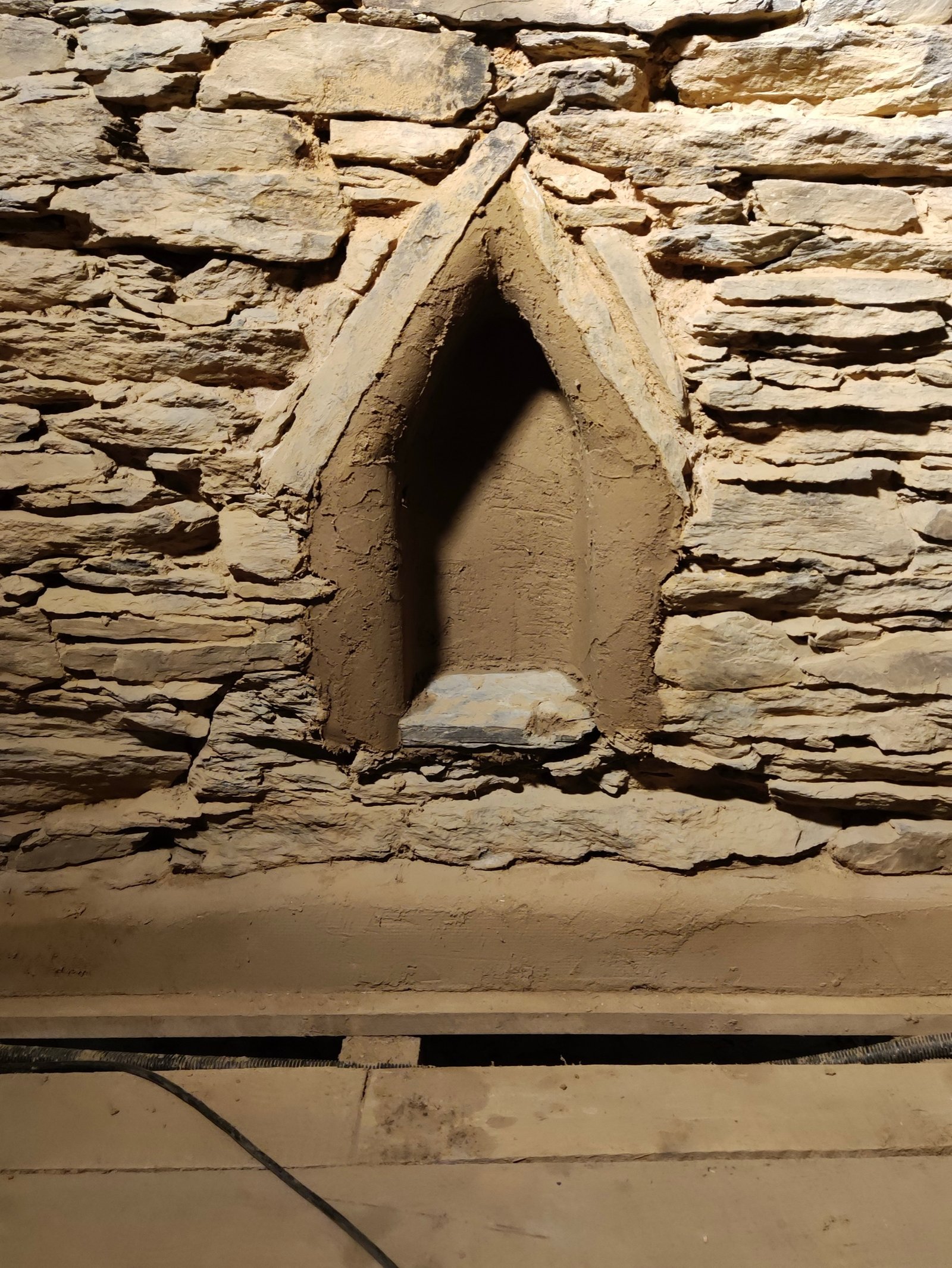 Historisches Bruchsteinmauerwerk mit spitzbogiger Nische innen, von oben beleuchtet