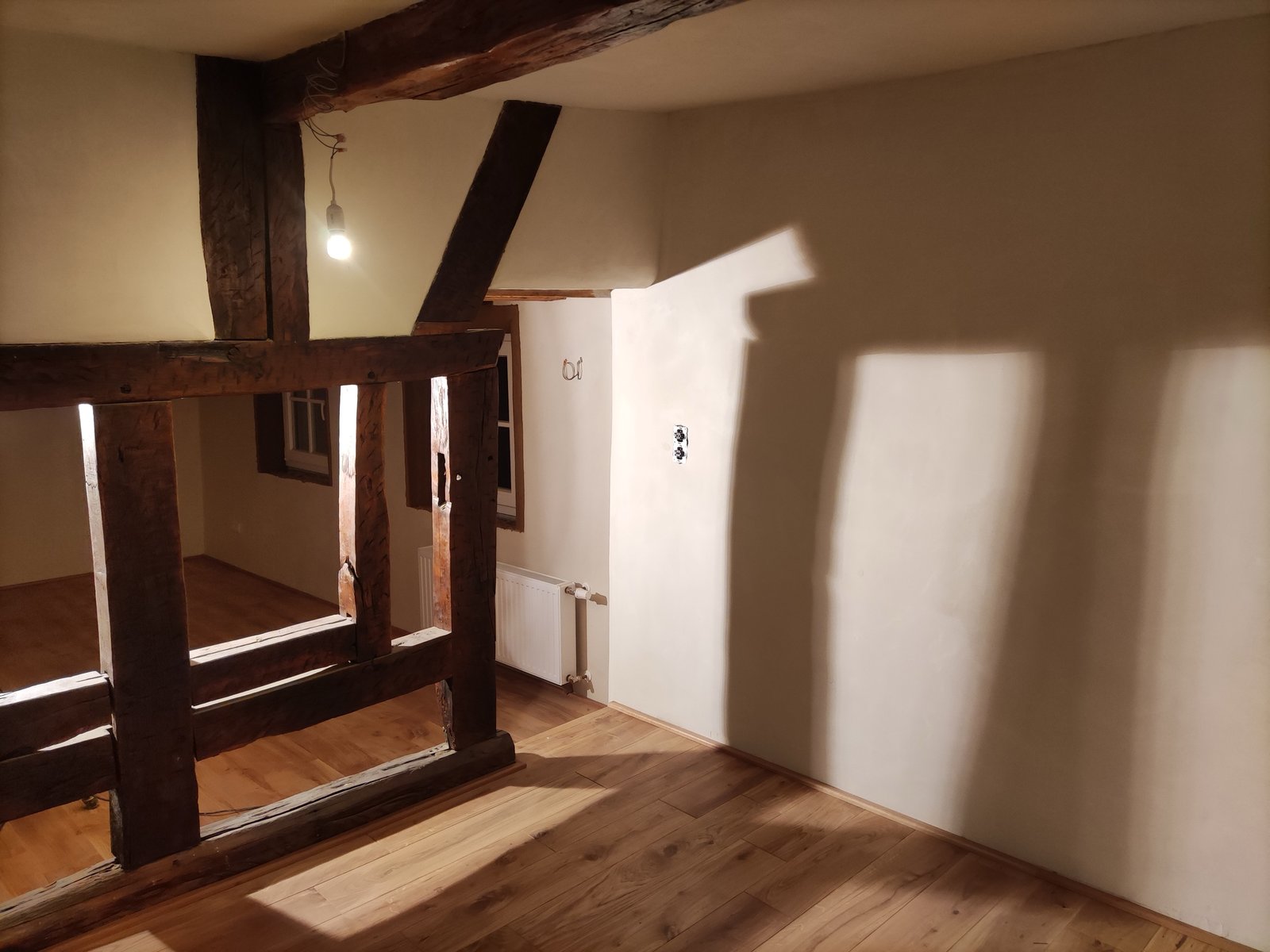 Fertig sanierter Wohnraum Fachwerkhaus: sichtbare Holzbalken, weißer Kalkputz, Dielenboden