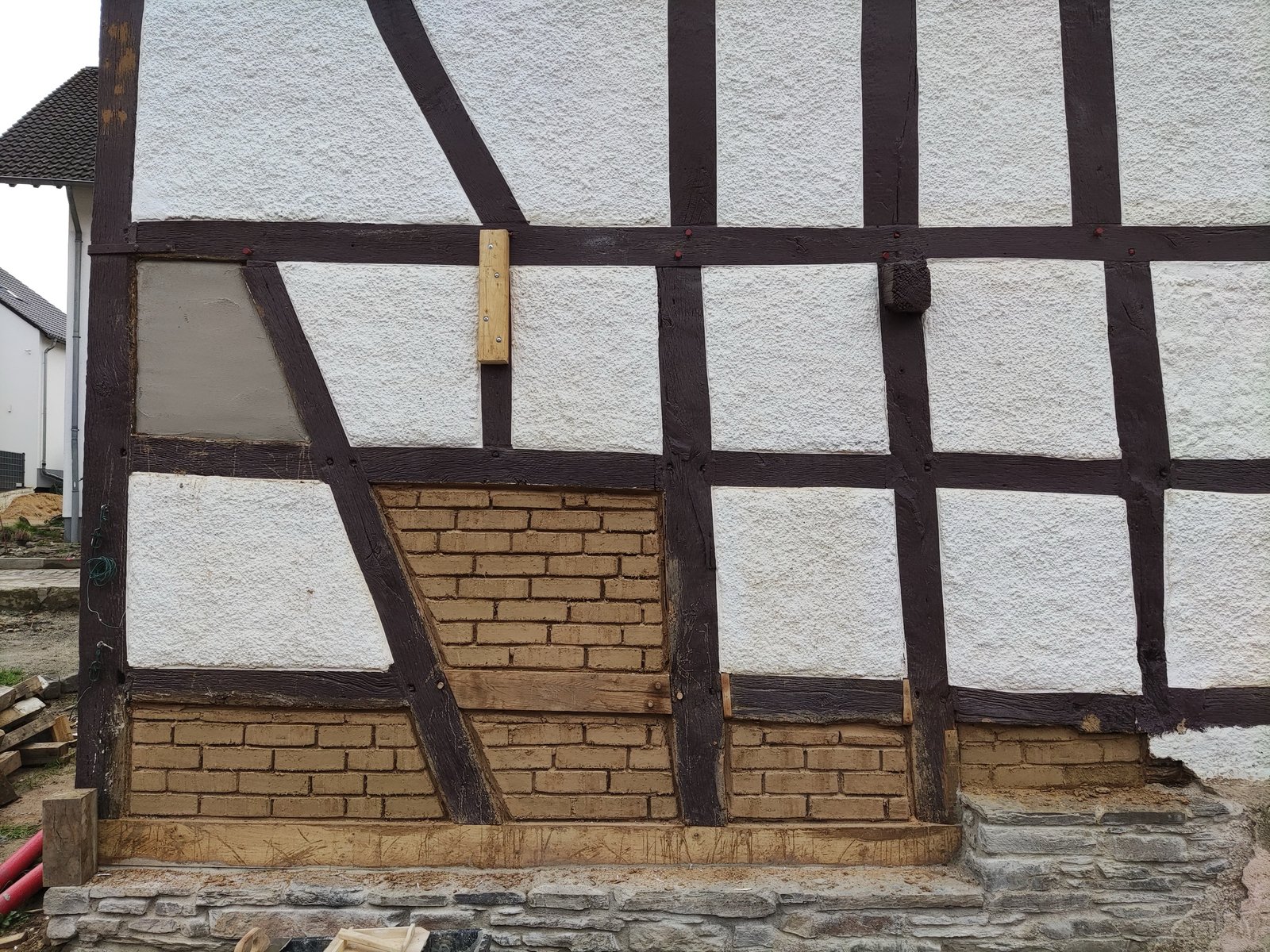 Fachwerkfassade im Ahrtal nach Sanierung: weiß verputzte Gefache, neue Lehmziegelfüllung