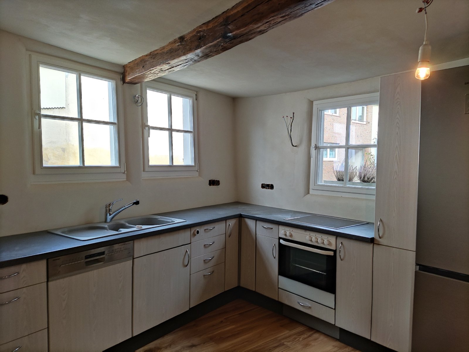 Fertiggestellte Küche im Fachwerkhaus: Holzbalkendecke, weiße Wandflächen, Kalkputz