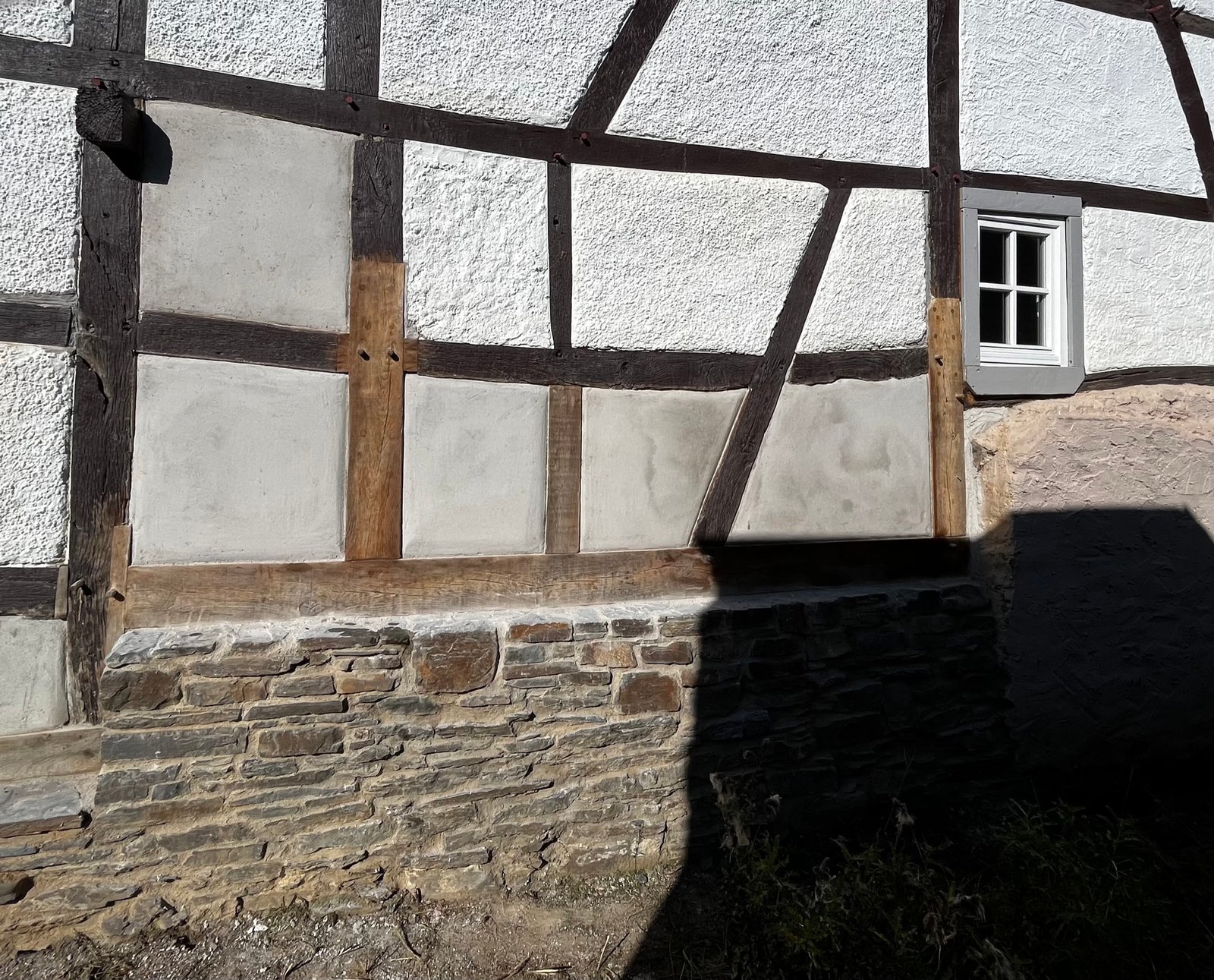 Fassadendetail nach Sanierung: weiße Putzgefache im Fachwerk, historisches Mauerwerk