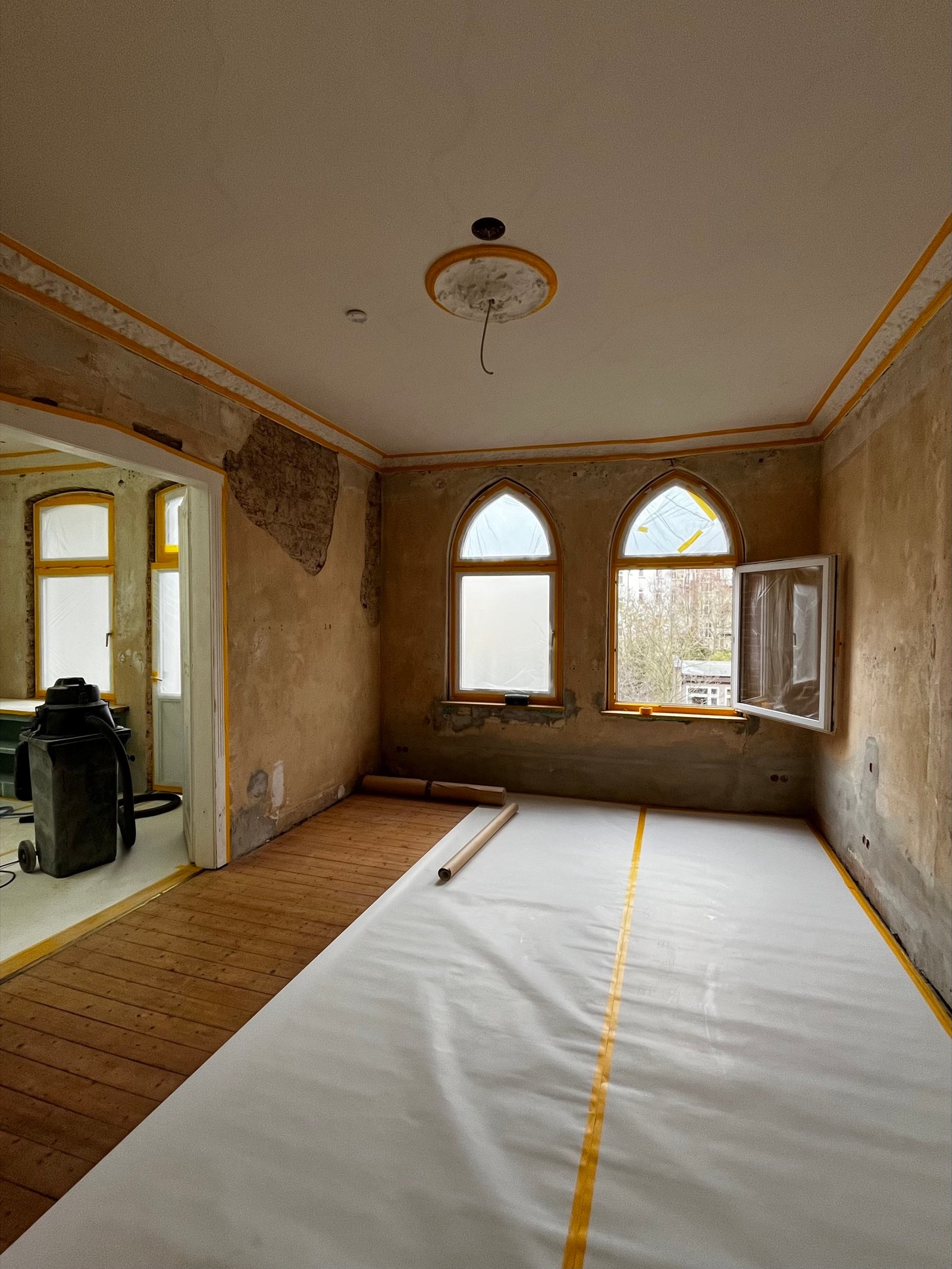 Altbau-Innenraum im Rohbauzustand: historischer Kalkputz abgelöst, Bögen mit Schutzfolie