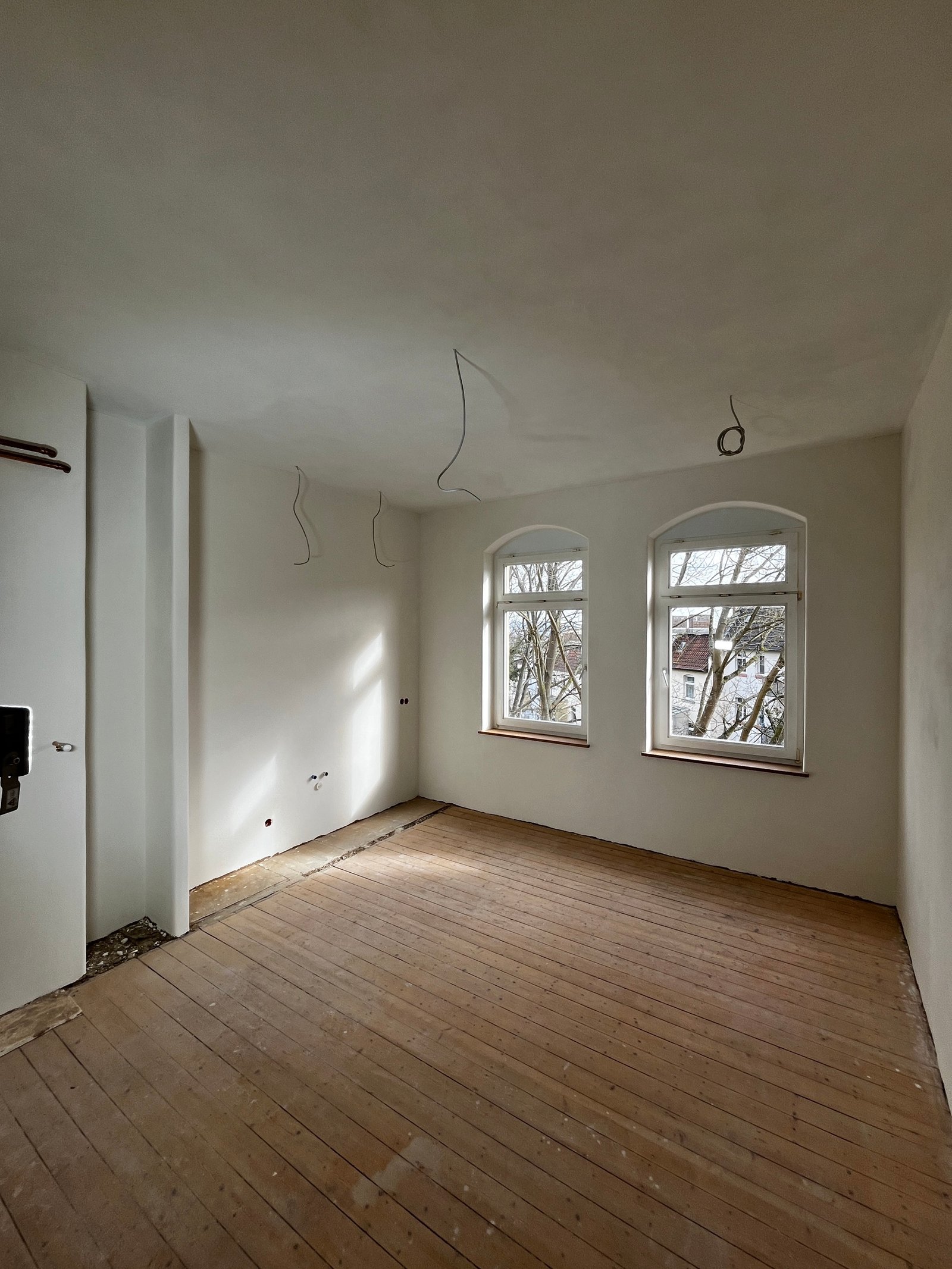 Gründerzeitlicher Raum nach Putzarbeiten: frischer Kalkputz, Rundbogenfenster-Öffnung