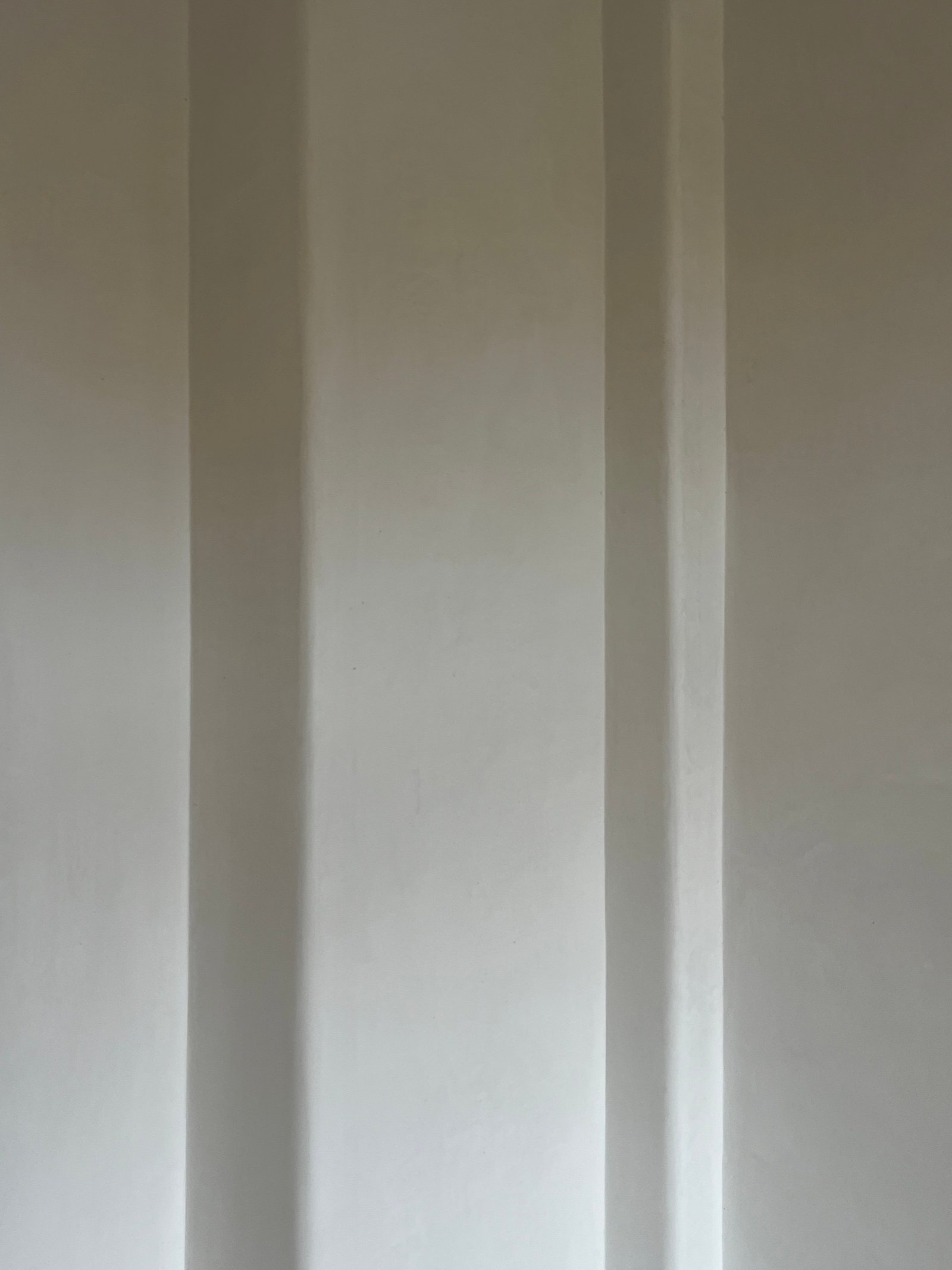 Fertig verputzte Wandfläche mit vertikalen Stuckprofilen, glatter Kalkputz, Altbausanierung