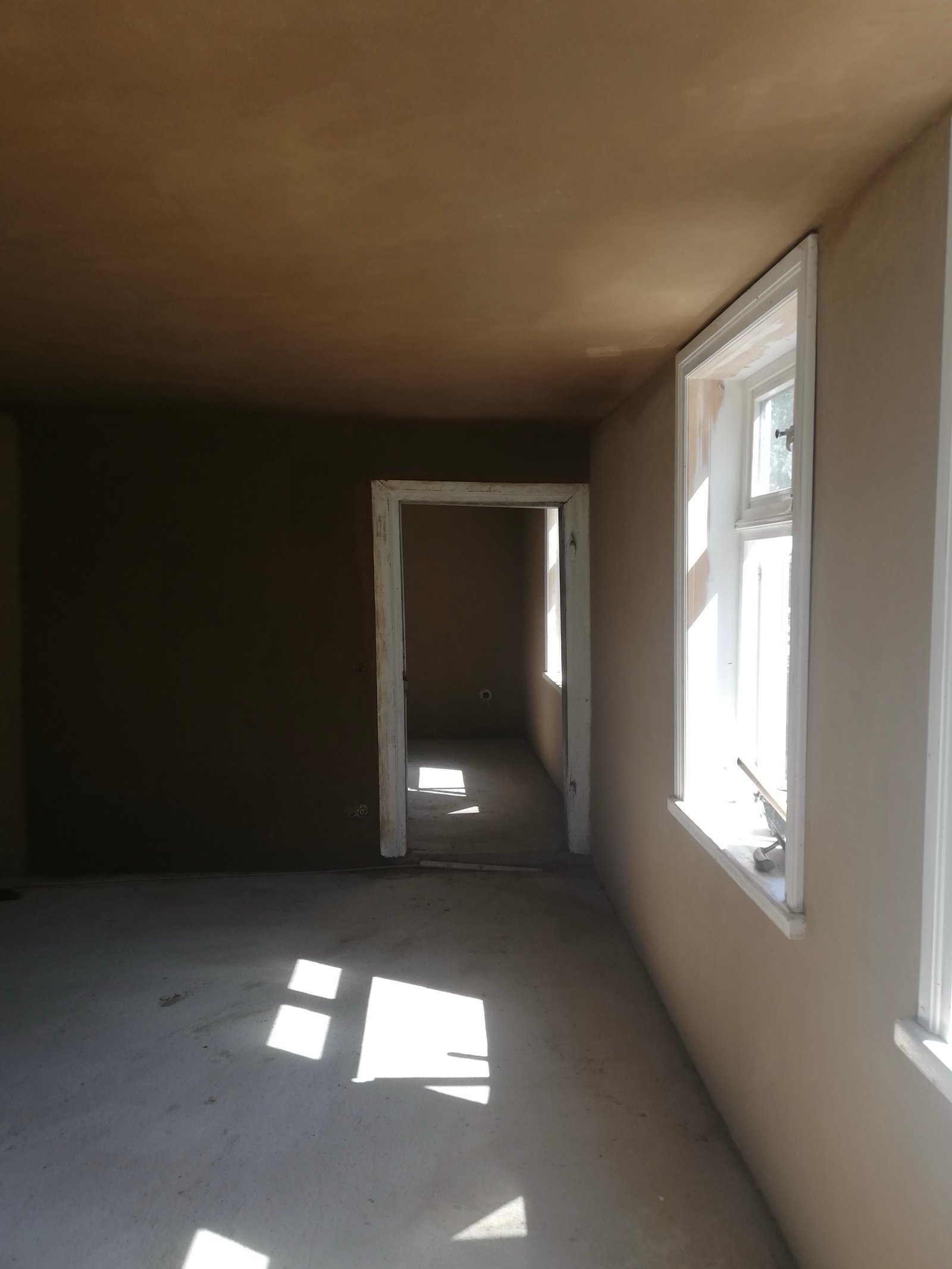 Sanierter Innenraum Fachwerkhaus Niedersachsen: Lehmputzwände, drei Fenster, Schubkarre