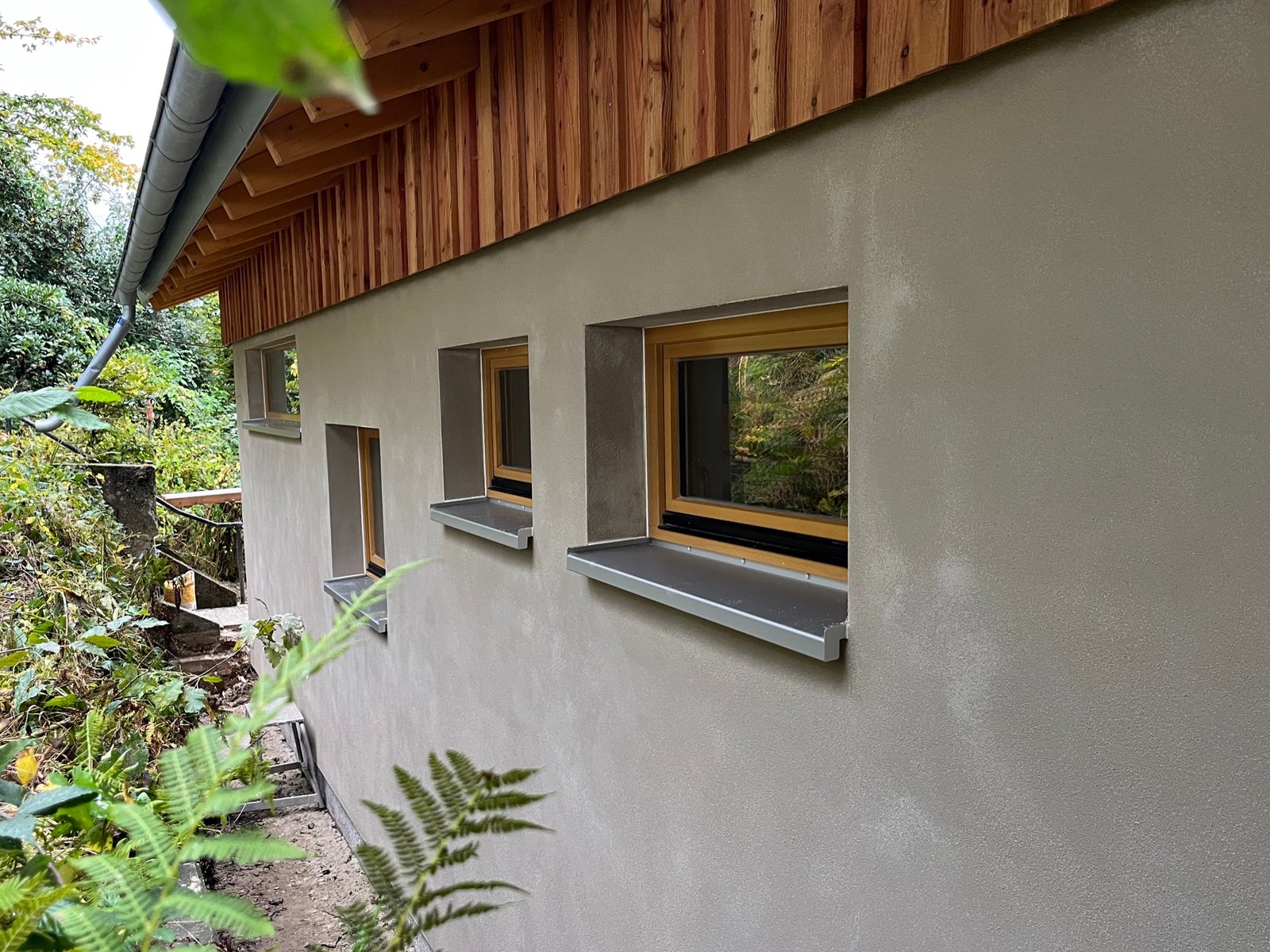 Holzhaus im Wald: Außenfassade mit Holzschalung und Holzfaserdämmung im Rohbauzustand