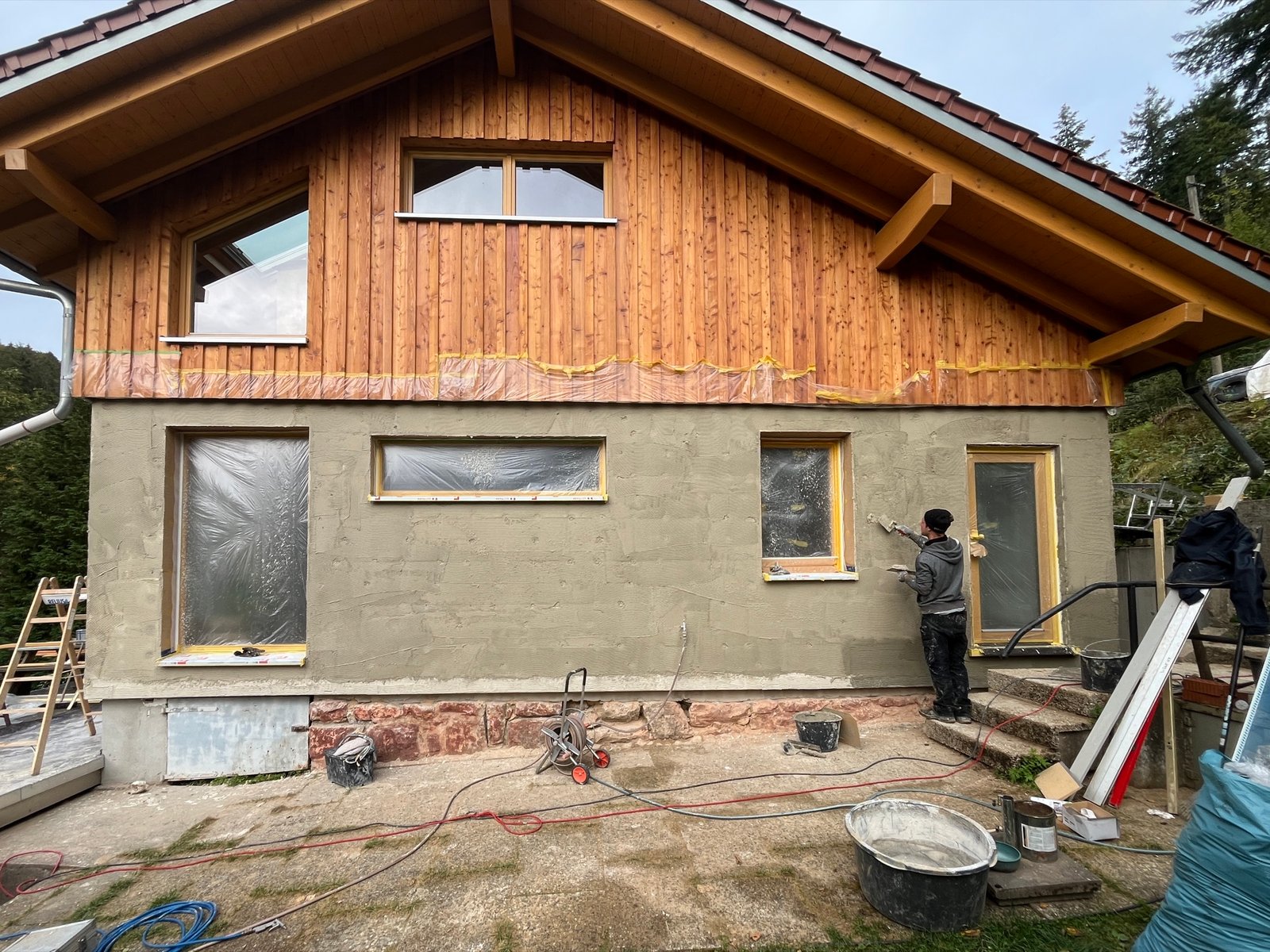 Kalkputz Oberputz auf Holzfaserdämmfassade: heller Grauton, Fensterrahmen sauber