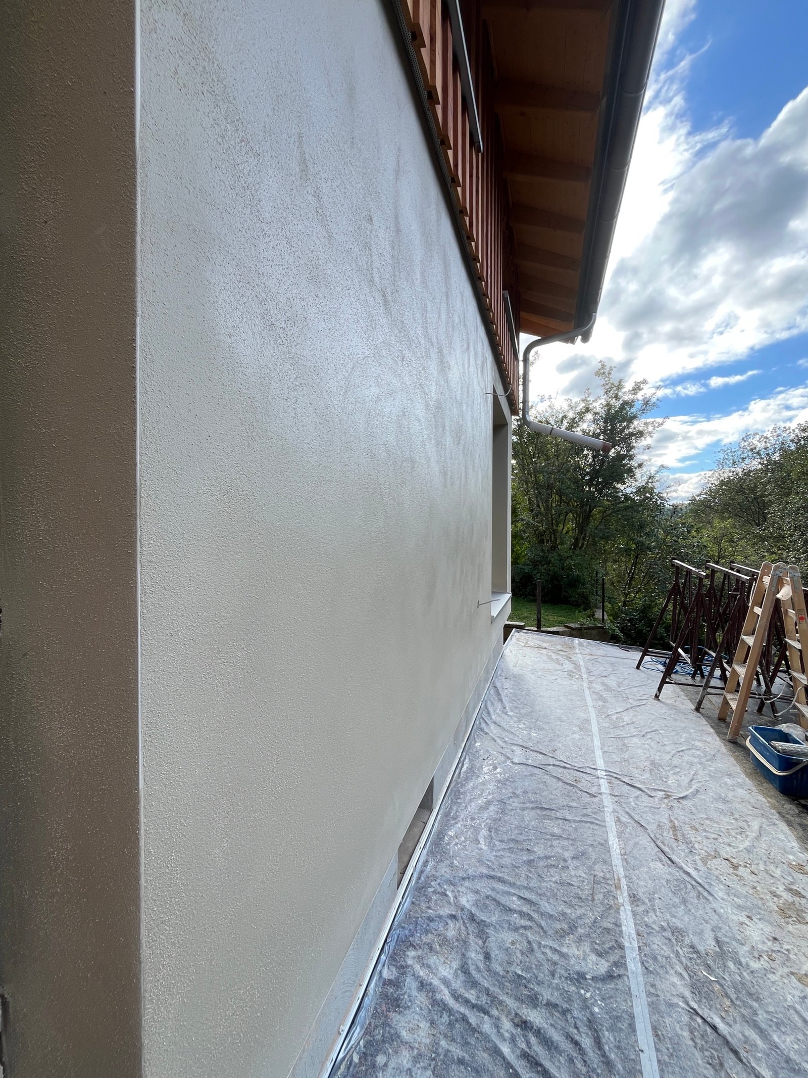 Fertige Kalkputzfassade mit Holzfassadenstreifen oben, Fenster und Natursteinvorsatz