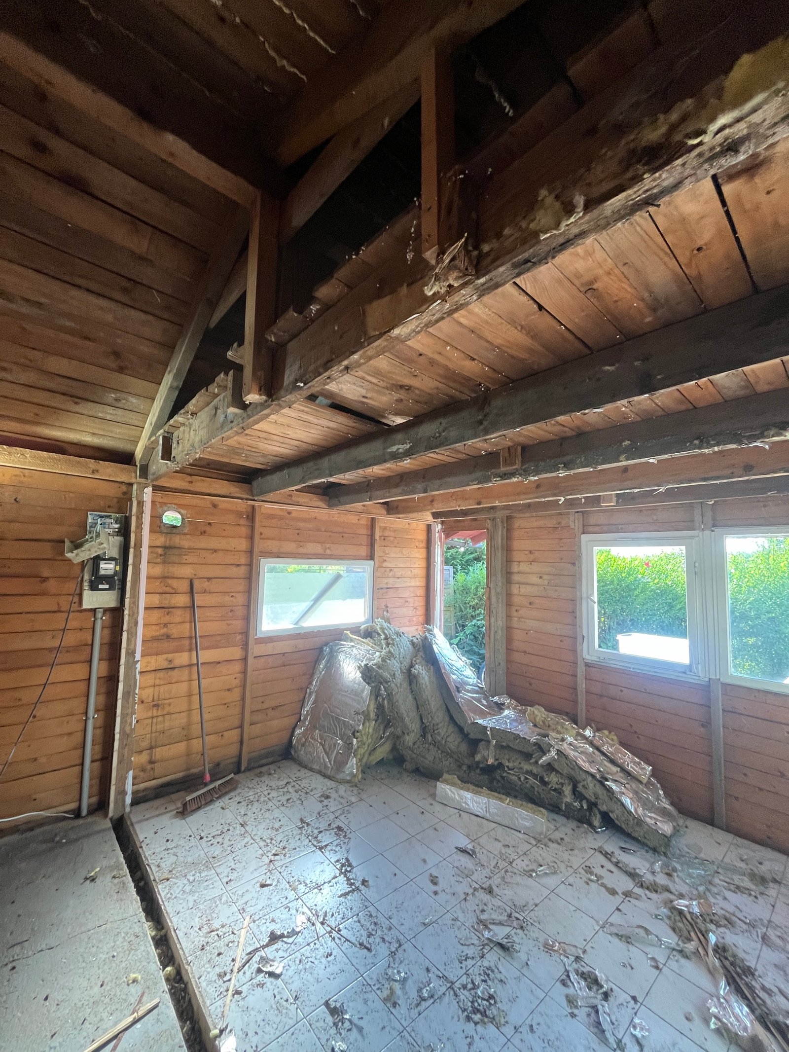 Gartenhaus-Dachkonstruktion von innen: verwitterte Holzbalken vor der Sanierung