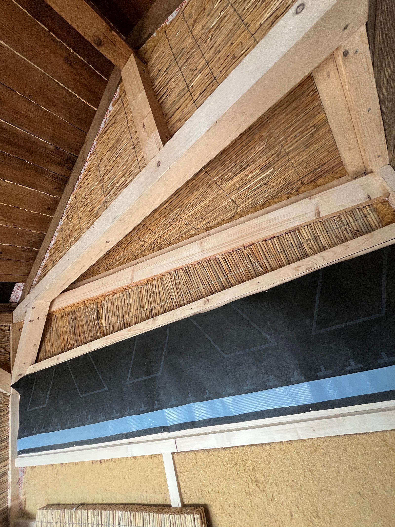 Gartenhaus: Lehmputz auf Schilfrohrwand aufgetragen, warmer Erdton, Putzauftrag