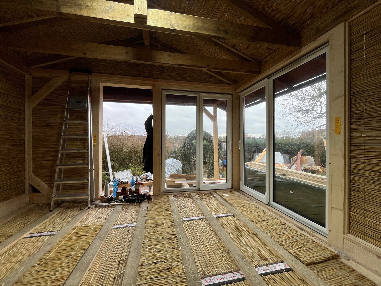 Gartenhaus-Fensterdetail innen: Holzverkleidung, Schilfrohr und Lehmputz-Laibung