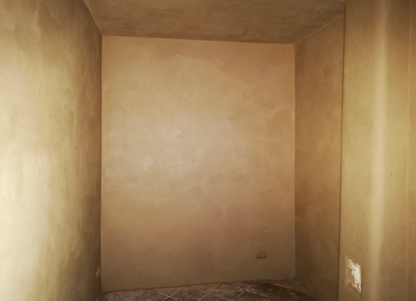 Lehmputzraum fertig: warm-goldener Farbton, Wände und Decke gleichmäßig, breiter Raum