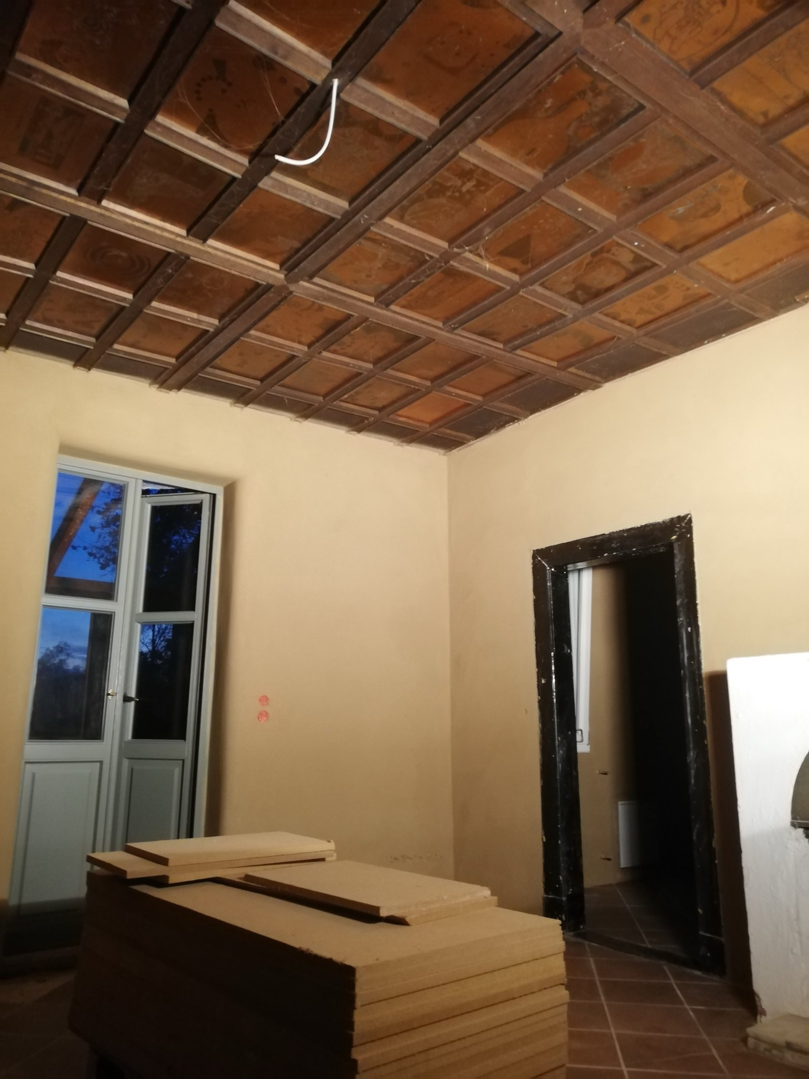 Lehmputzraum mit historischer Holzdachkonstruktion und Terrakottaboden, Ziegeltöne