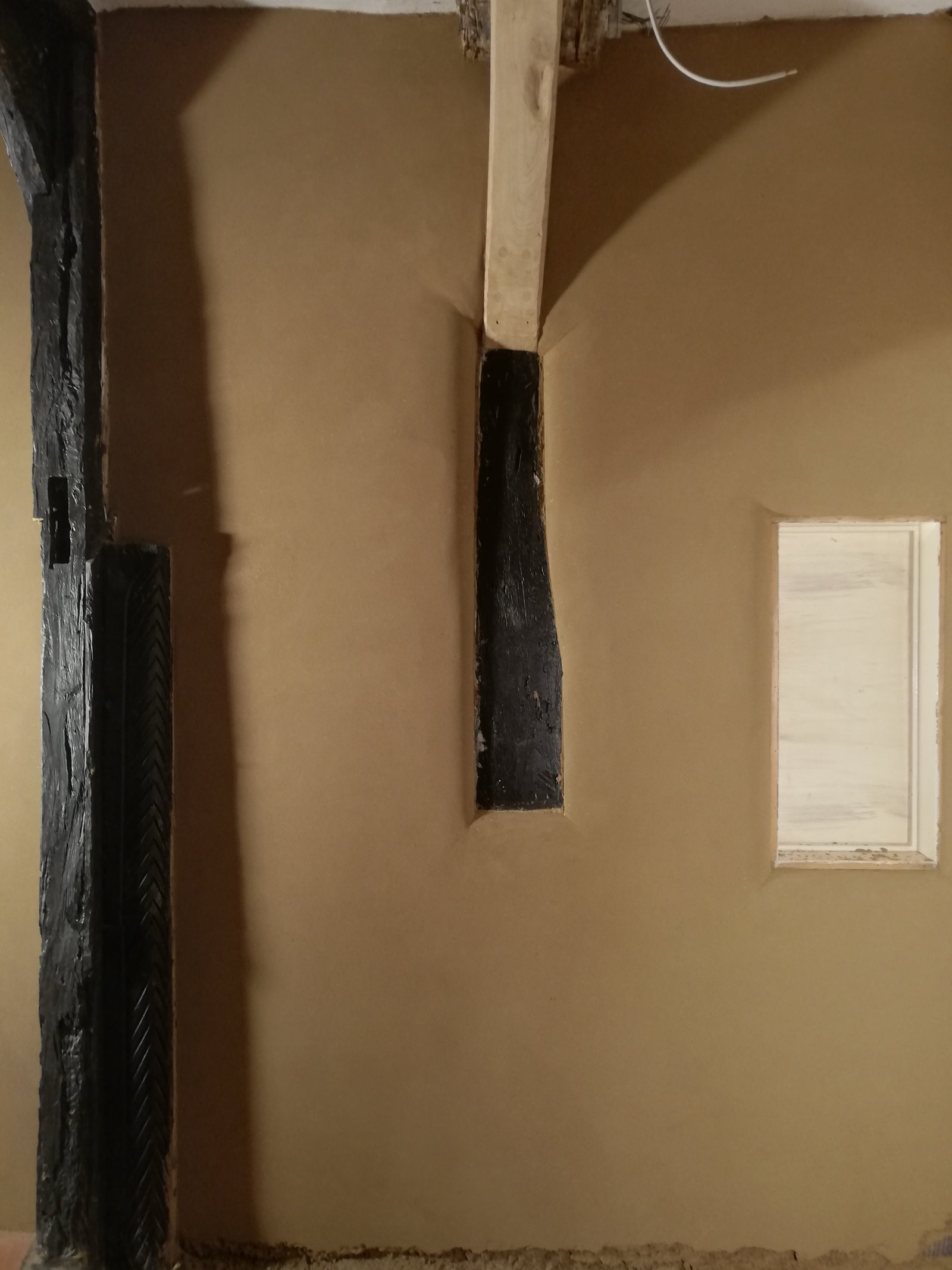 Lehmputzwand im Künstlerhaus: schwarze Holzbalken, kleine Fensterlaibung, fertig