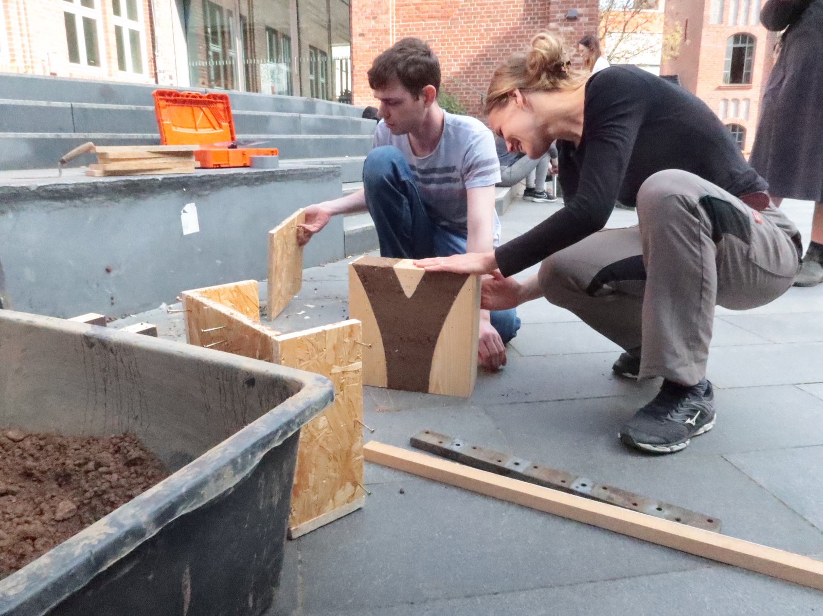 Stampflehm-Workshop: zwei Studierende entformen Y-förmigen Stampflehmkörper