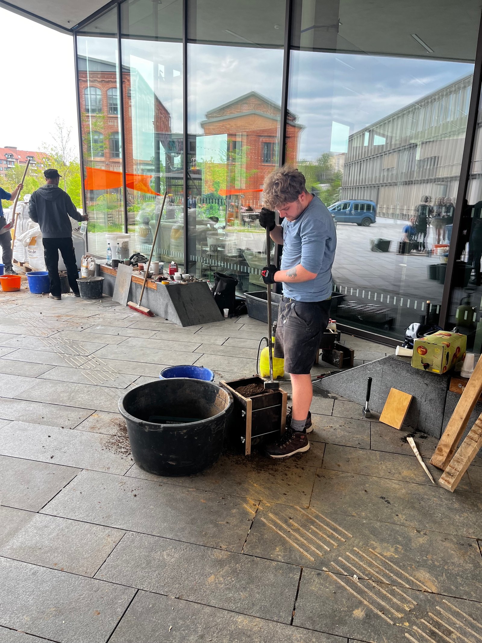 Stampflehm-Workshop: Studierender knetet und stampft Lehmmasse in Box