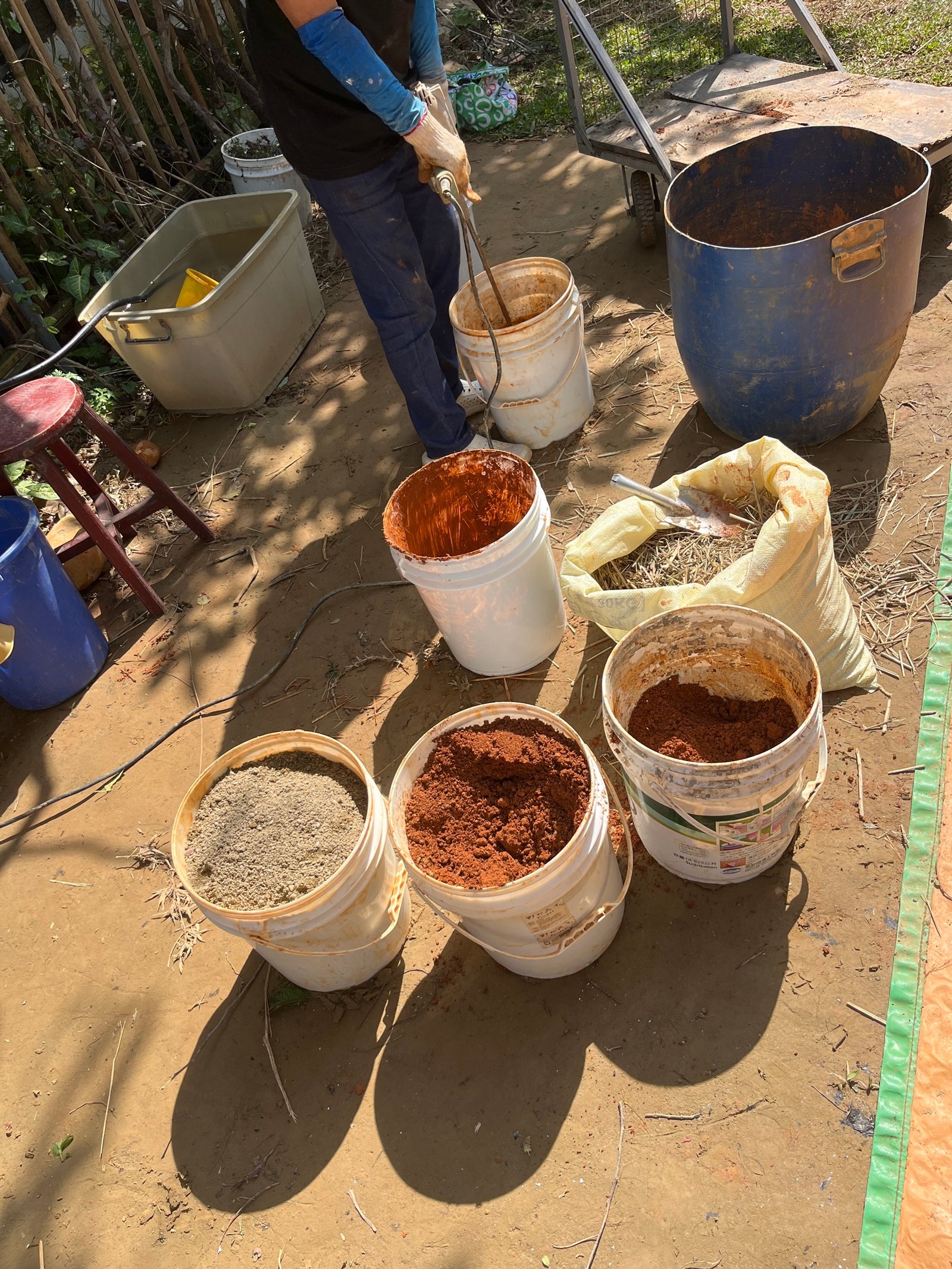 Lehmaufbereitung Taiwan: mehrere Eimer mit verschiedenen Lehmproben und Sand