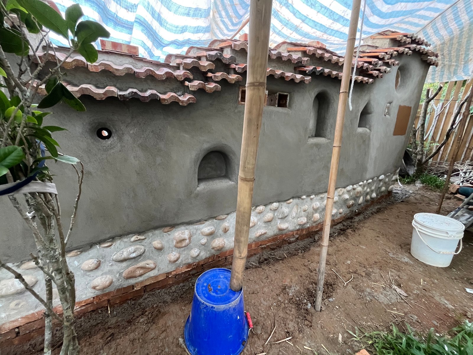 Stampflehmwand fertig: gerundete Formen, Wandnischen, Kieselsockel, Gesamtansicht