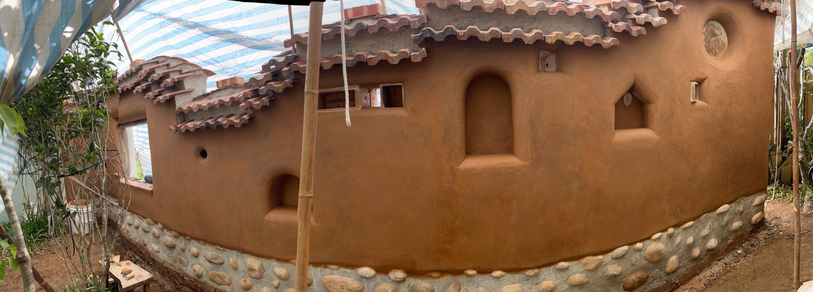 Panorama fertige Lehmwand Taiwan: runde Formen, Nischen, Kieselsockel, Dachziegel